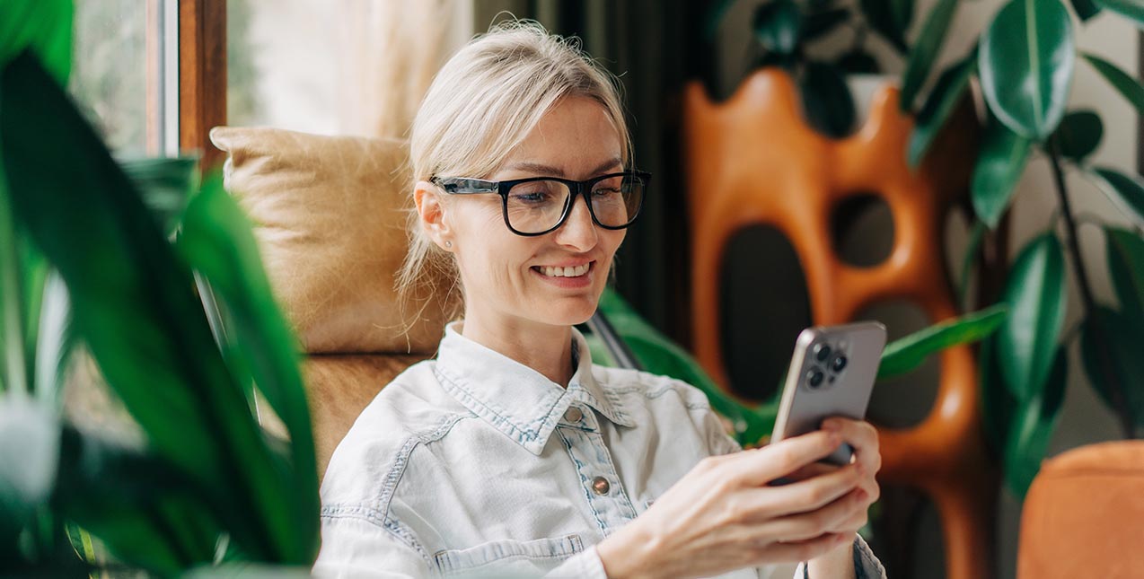 Blonde woman in glasses looking at mobile phone