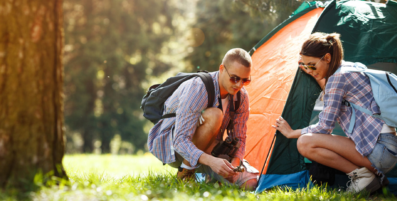 Two people setting up camping tent
